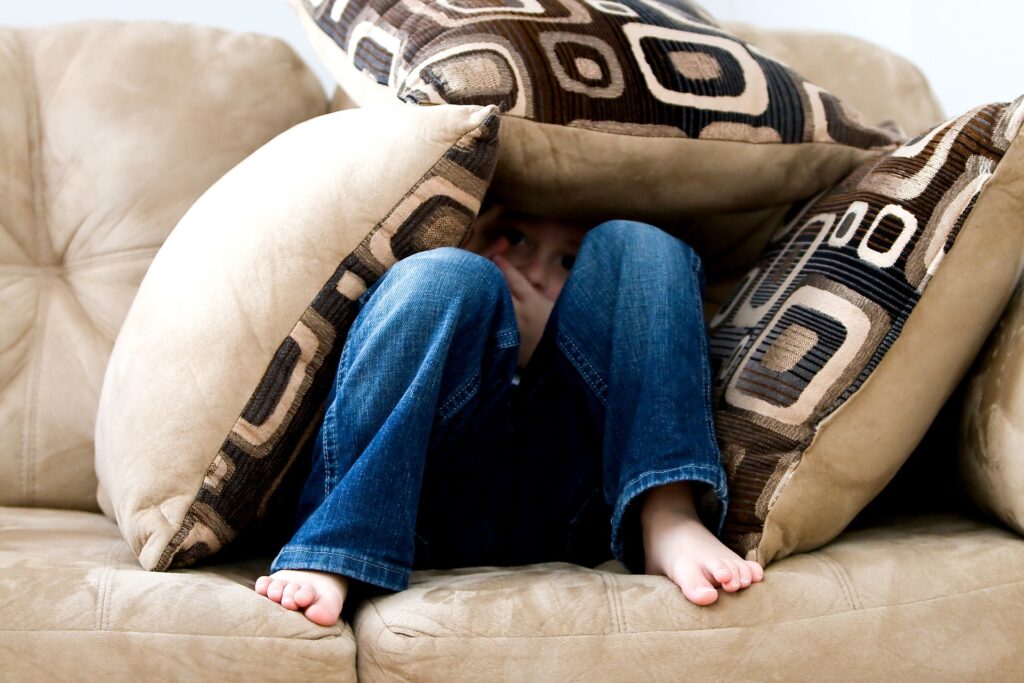 enfant caché sous des oreillers sur un canapé